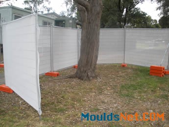 Welded portable fences with shade cloth are installed surrounding a tree. 